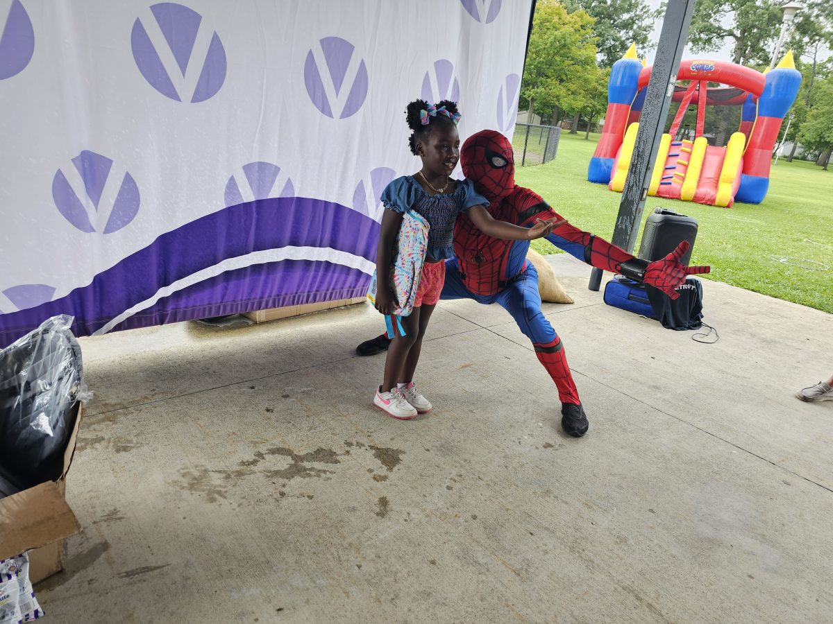 Spiderman posing with little girl with vitiligo during Back to School backpacks giveaway in Detroit