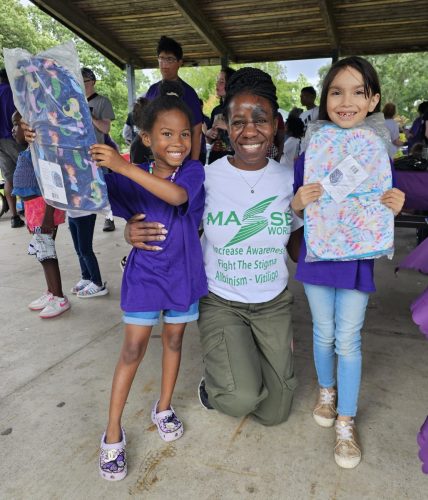 Raissa presenting backpacks to children with vitiligo in Detroit in June as part of the Masse World Back to School program