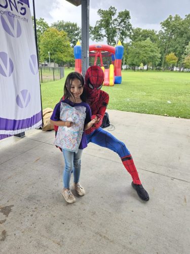 Spiderman posing with girl during Back to School backpacks giveaway in Detroit 