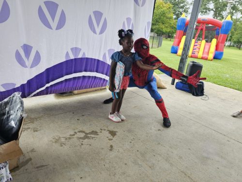 Spiderman posing with little girl with vitiligo during Back to School backpacks giveaway in Detroit